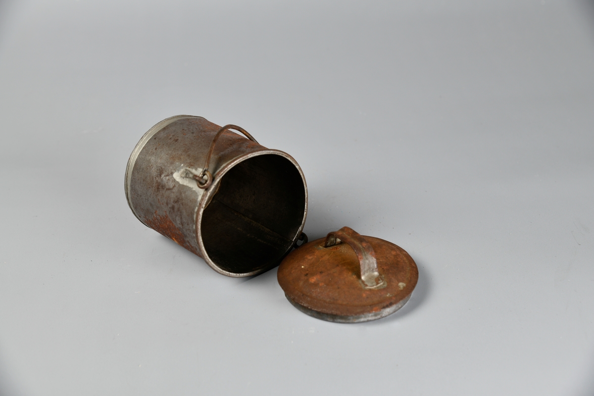 Spann med lokk. Håndtak på lokket og på hver side av korpus. Lokket er løst. Flere slike spann har blitt registrert som melkespann på Digitalt museum. Det er en del rust på oversiden av lokket og den ene siden av spannet.
