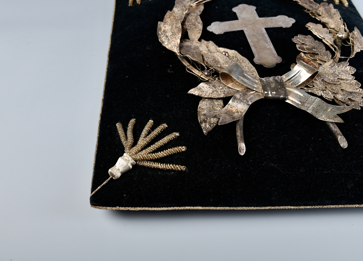 Sølvkrans av laurbær og eikeløv med sløyfe nederst. Mellom de bøyde greinene er det et sølvkors. Kransen er sydd ned på en svart fløyelspute med dusker i hjørnene. Sølvsnor påsydd rundt puta.

Det finnes to like kranser som denne publisert på Digitalt museum. Den ene er udatert, men den andre er også produsert i 1924 - og befinner seg på Mjøsmuseet.