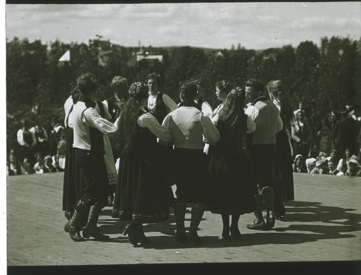 Kvinner og menn i bunader danser leikaring..