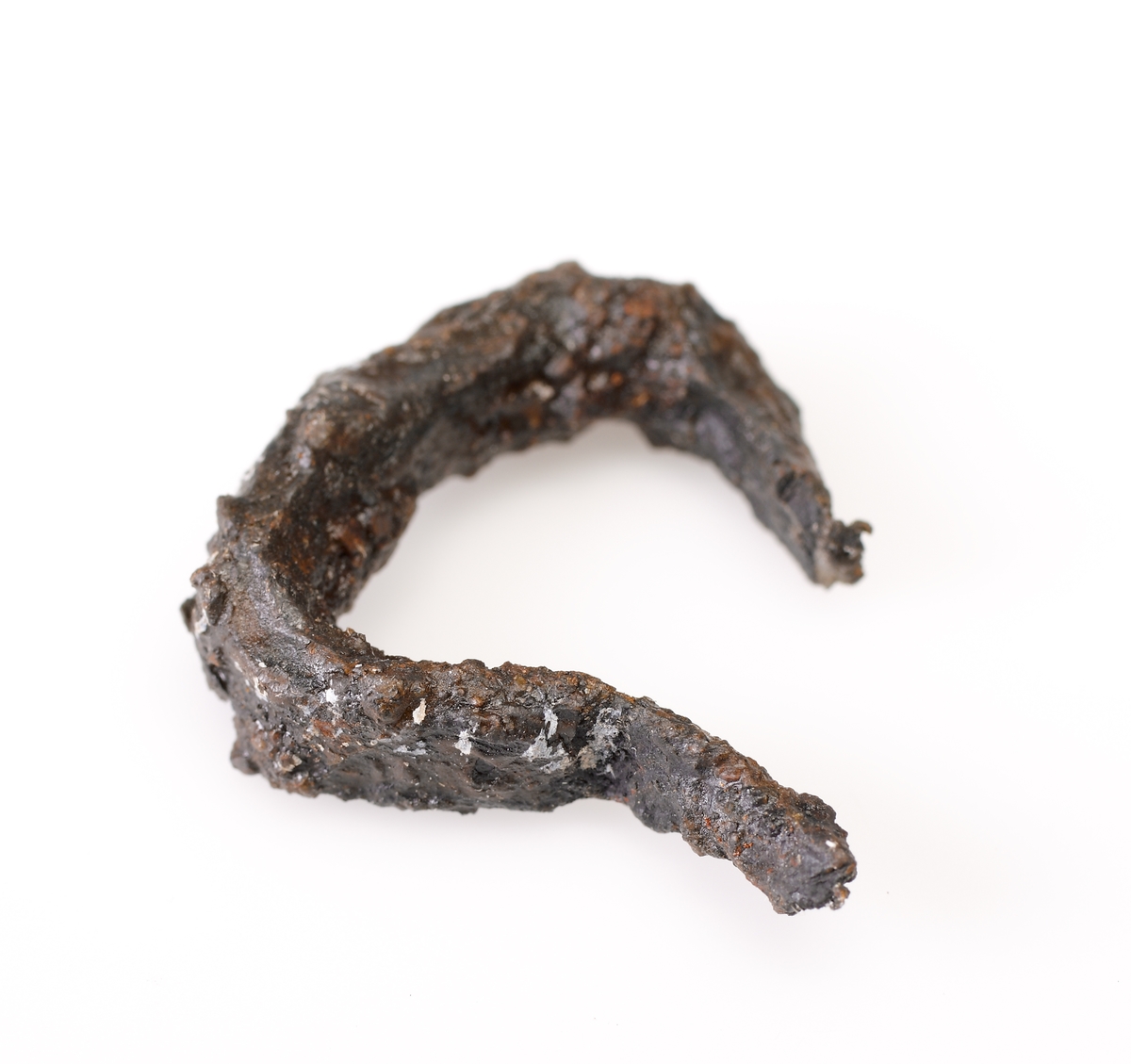 Del av en mungiga. Endast bågen och ansats av ena skänkeln bevarad. Starkt vittrad.