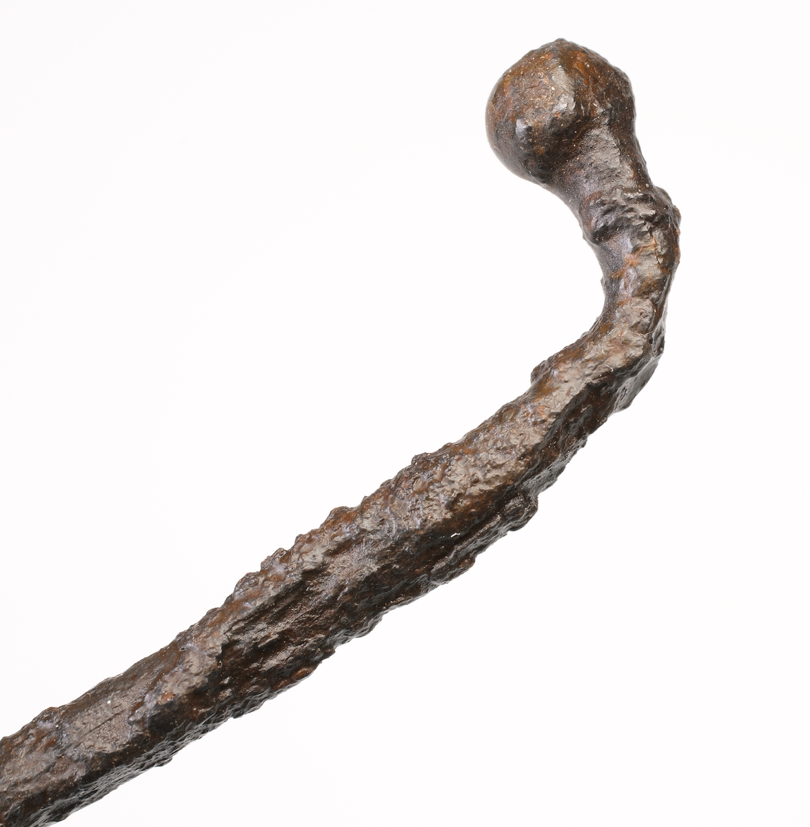 Rund böjd ten som avslutas med en ändknopp i ena änden. Anda änden rätvinkligt böjd och överst gängad och försedd med ett vinkelrätt utskott. Detta utskott är avslutat med en nu ofullständig rund platta med hål. Troligen en avtryckare till ett armborst eller annat handvapen.