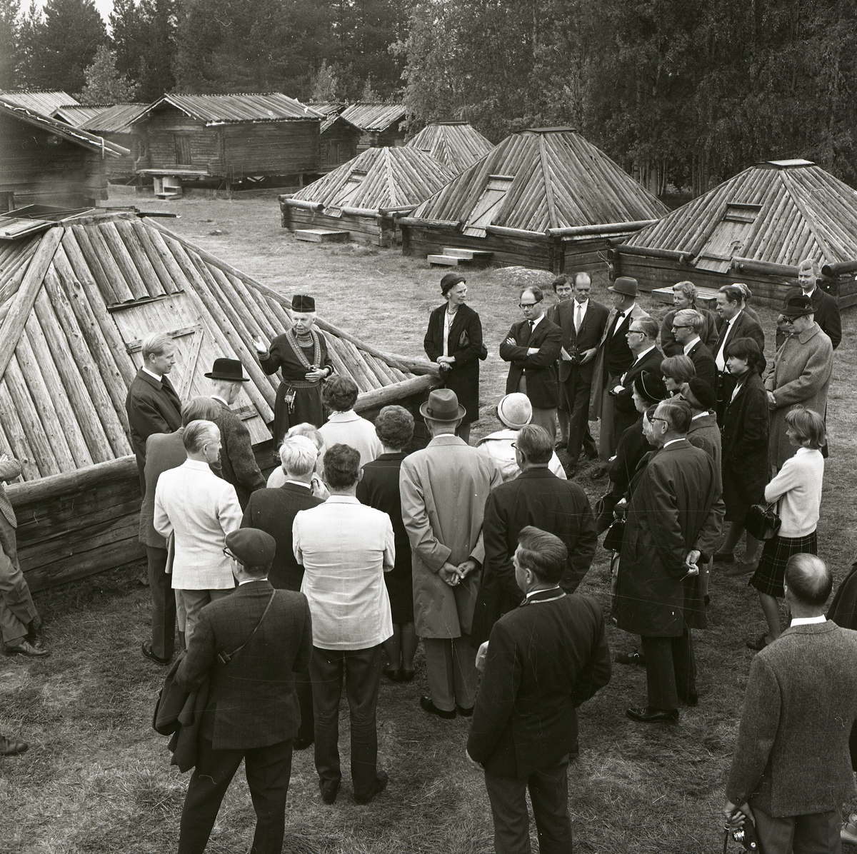 En kvinna iförd traditionell samisk klädsel pratar inför en samling människor i Lappstaden i Arvidsjaur.