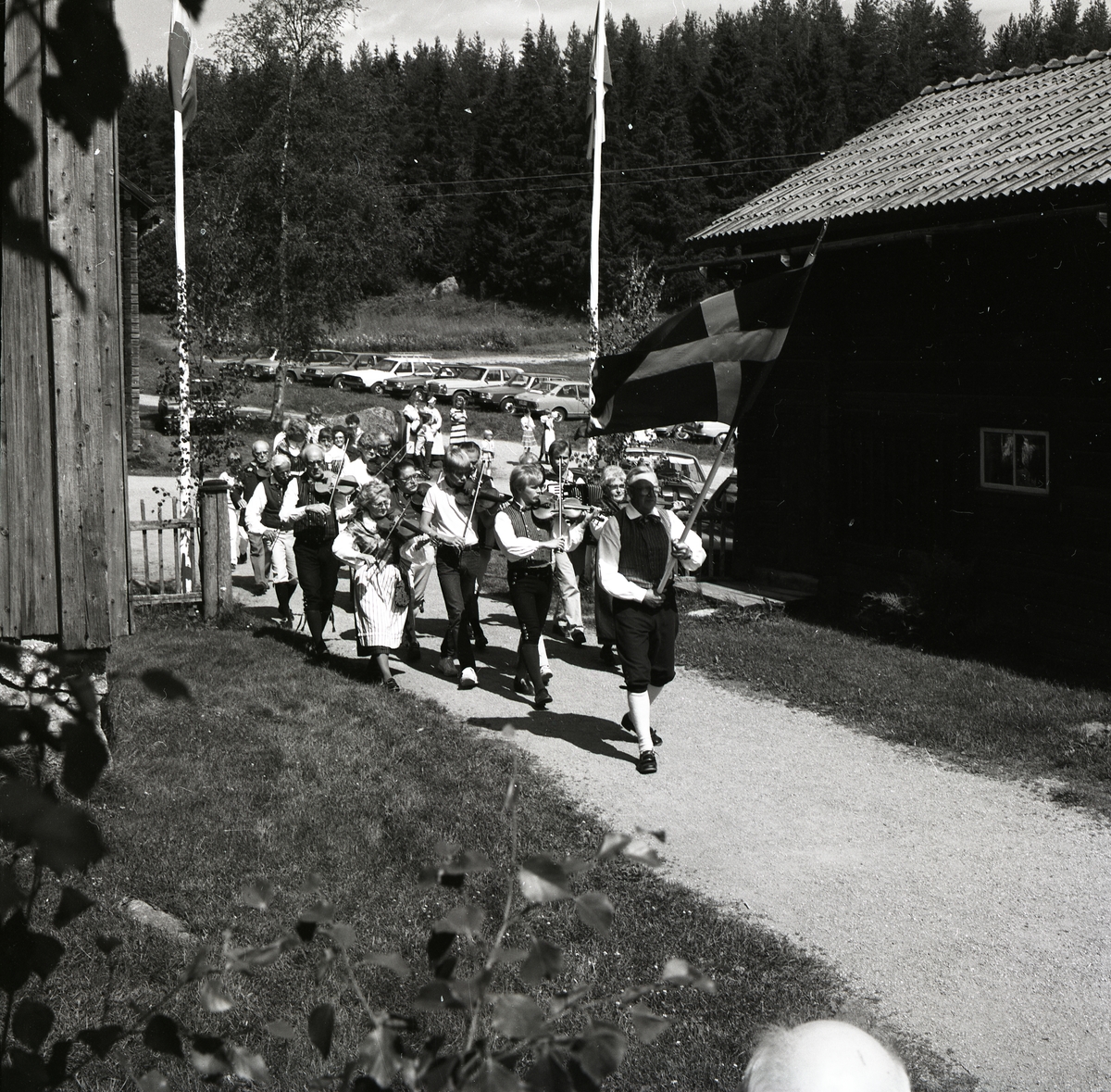 En grupp fiolspelare marscherar under den svenska flaggan vid Rengsjöfesten, 17 juli 1983.