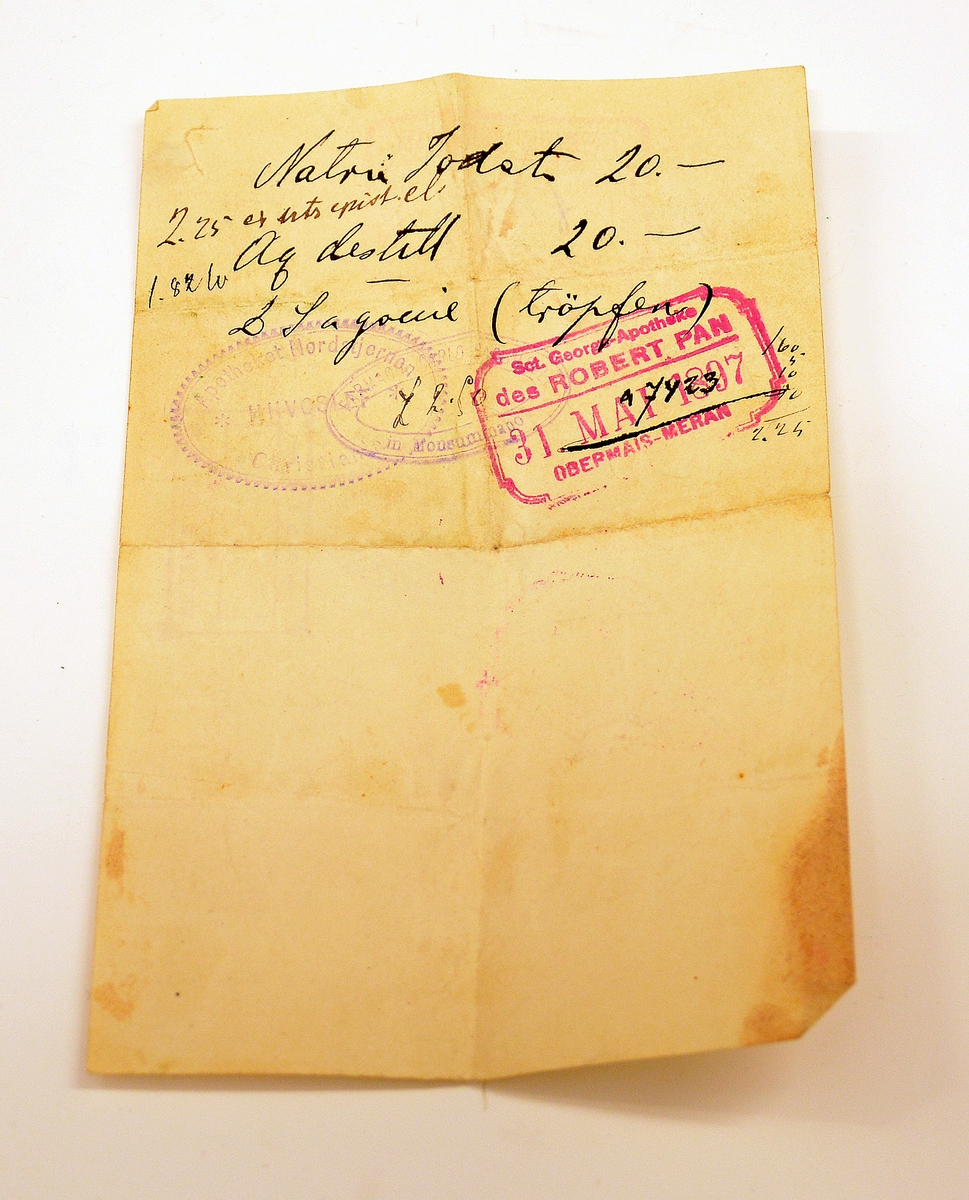 Liten lommebok i grønt skinn med to rom, mosegrønt fôr. Utsiden med preget dekorrender i gull. En side mangler sømmen.
Innlagt konvolutt med to resepter fra Henrik Ibsens privatlege, Dr. med. Edvard Bull. Den ene resepten datert 14/3 1903. En tredje resept, italiensk, datert 31. mai 1897.