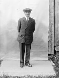 Portrett av ukjent mann. Fotografens bakteppe synlig, hengt 