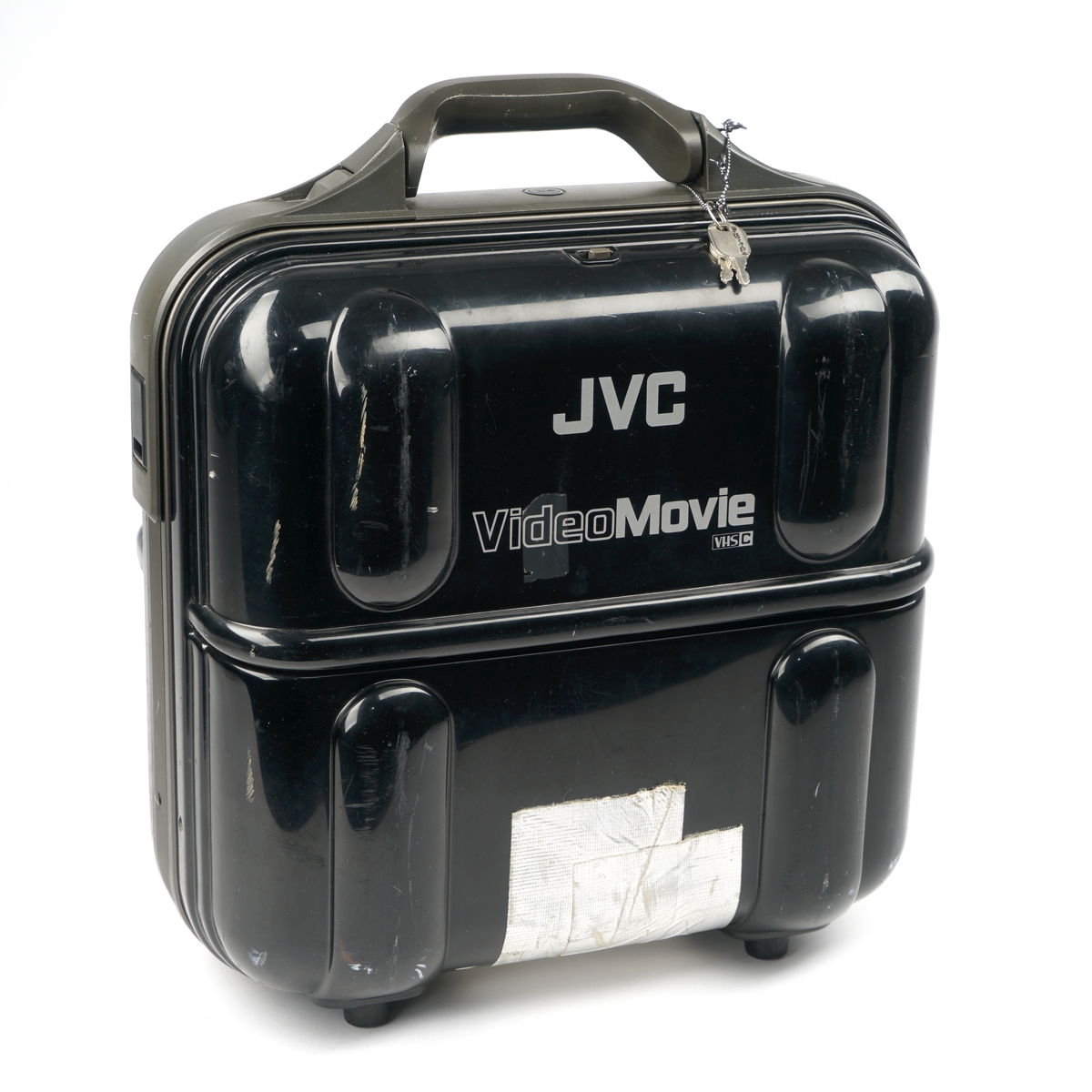 Videokamera med bæresele og med okkular og linse samt diverse funksjonstaster . Luke på siden for isetting av videokasett. En kasett sitter i kameraet. Kameraet ligger i en låsbar ( to nøkler medfølger) plastkoffert sammen med  tre ulike funksjonskabler sammen med et strømadapter. I kofferten er det et eget rom for et kassettadapter som igjen ligger i et etui. I adapteret ligger det en kassett. Videre medfølger det et tomt kassettetui samt ett etui inneholdene en kassett.