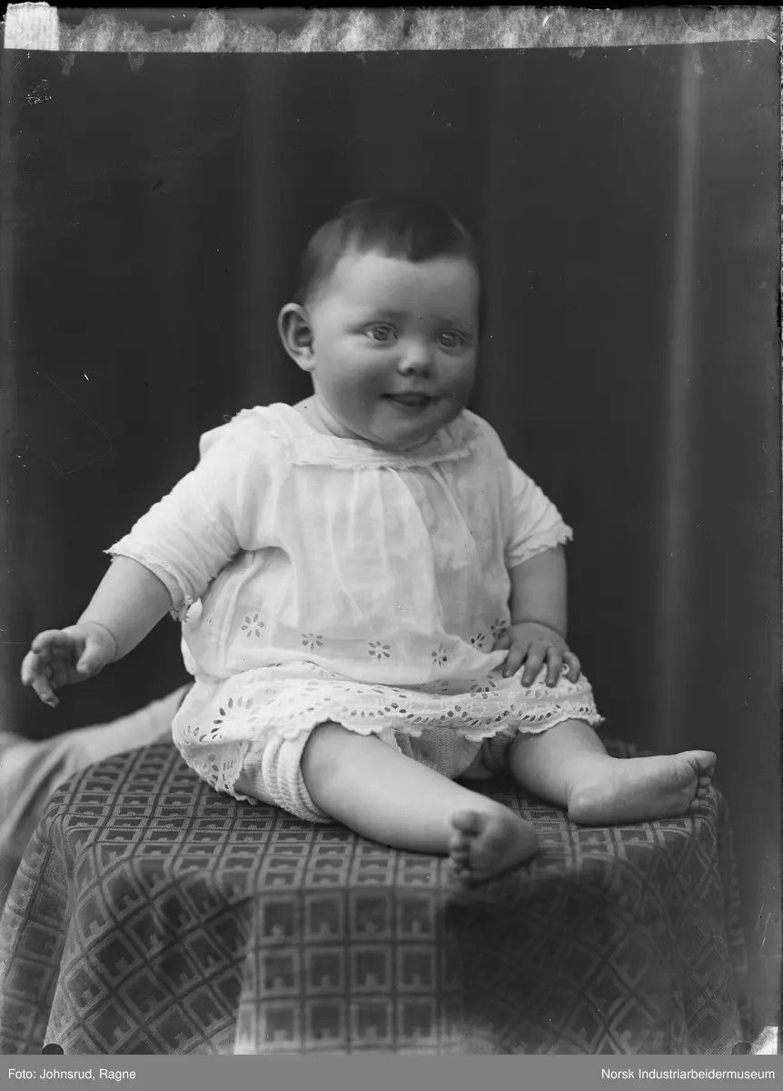 Portrett. Baby sittende med kjole.