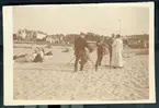 Fyra herrar på en sandstrand, T Boije Hjertström till höger, i samtal med kvinna i ljus badrock.