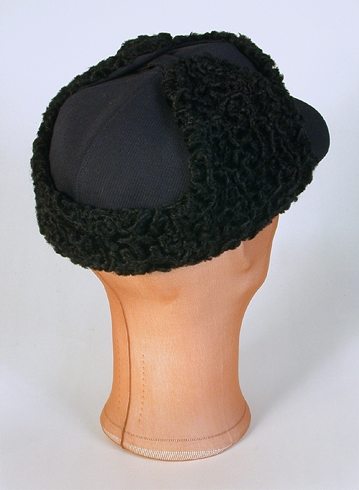 Sportmössa för man av blått ylletyg, kilskuren kulle. Tygklädd skärm. Uppvikt brätte klätt med krimmer. Påsydd prislapp. 
Mått: Runt kullen 590 mm. Kullens höjd 90 mm. 
Storlek: 61.