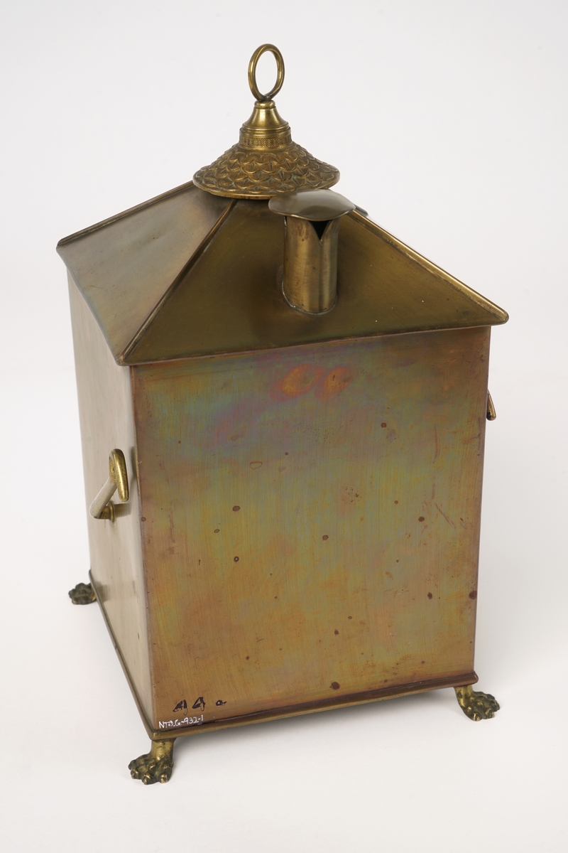 Firkantet kompasshus av metall med dør med vindu av glass. Døren kan låses med krok. Fire forsirede føtter av metall.  Tak som skråner til alle fire sider med vindu på takets forside. Luftavtrekk. Toppen av taket er utstyrt med forsiret deksel med bærering. To støttekroker, èn på hver side. Inne i huset er det to stearinlysholdere med metallfjær-innretning. Mellom disse er det fastmontert et metallrør.
Videre medfølger det to støtteklosser av tre for kompasset. Kompasslokk følger også med.