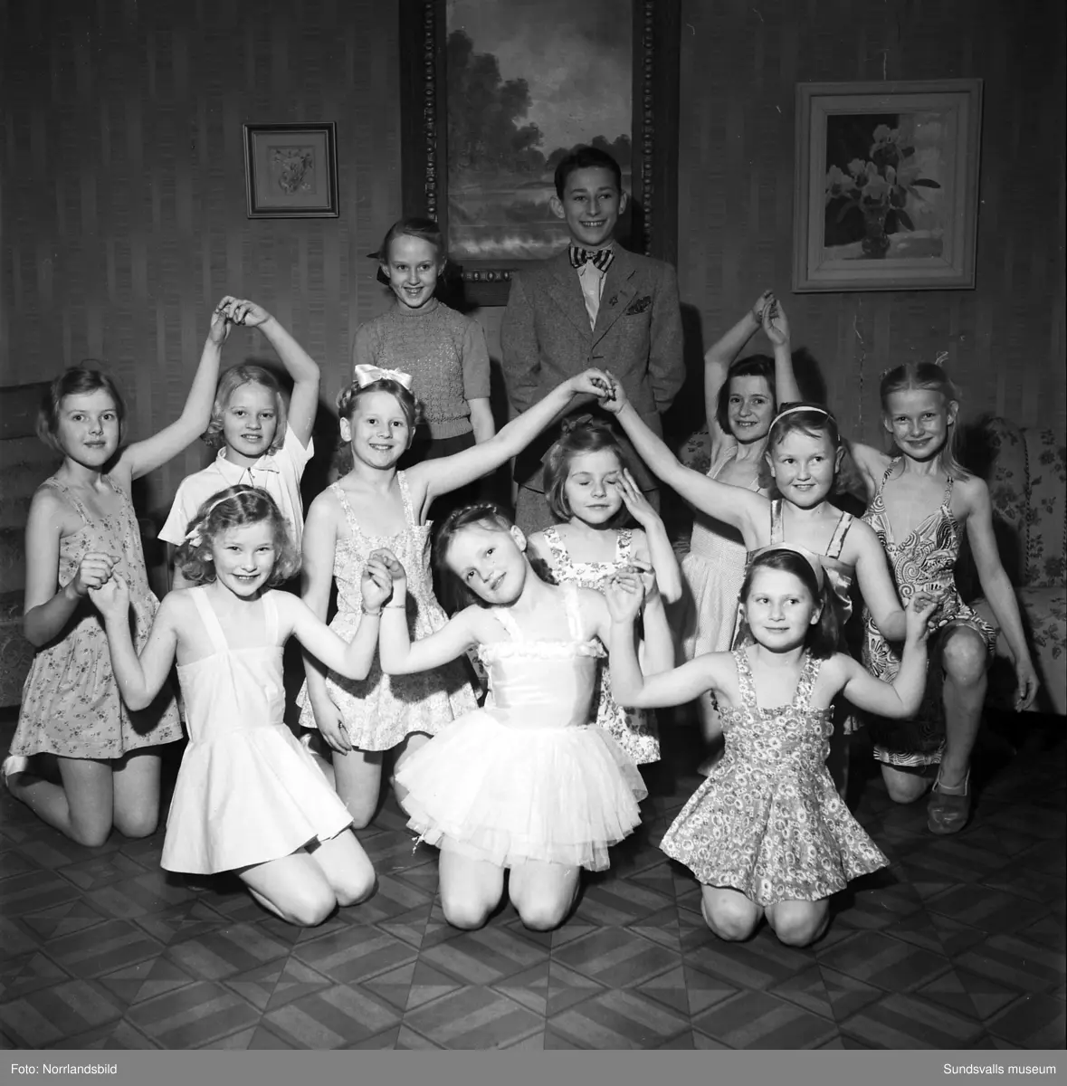 Barnteaterträning hemma hos fru Dagny Norberg i Ortviken, Skönsberg. Bild 1, längst bak: Marianne Rydberg och Lars Carlsson. Övriga från vänster: Britt Renman, Margareta Hammarström, Margareta Eriksson, Britt Jonsson, Britt-Mari Lundberg, Birgitta Bäckström, Monika Ödberg, Doris Norrgård, Marianne Norrgård och Ann-Mari Olsson. Bild 2: Dagny Norberg.