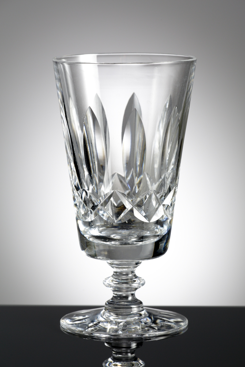 Konformad hög kupa, kort ben med knapp.
På kupan stående skärslipade "spetsiga ellipser", nederst på kupen en bård av brillianter. Runt foten slipade "spetsiga ellipser".
Helkristall med högt blyinnehåll som ger tyngd åt glaset.
Fotografierna: David Lönnquist under sliparbetet. På gruppbilden står Lönnquist längst till höger.