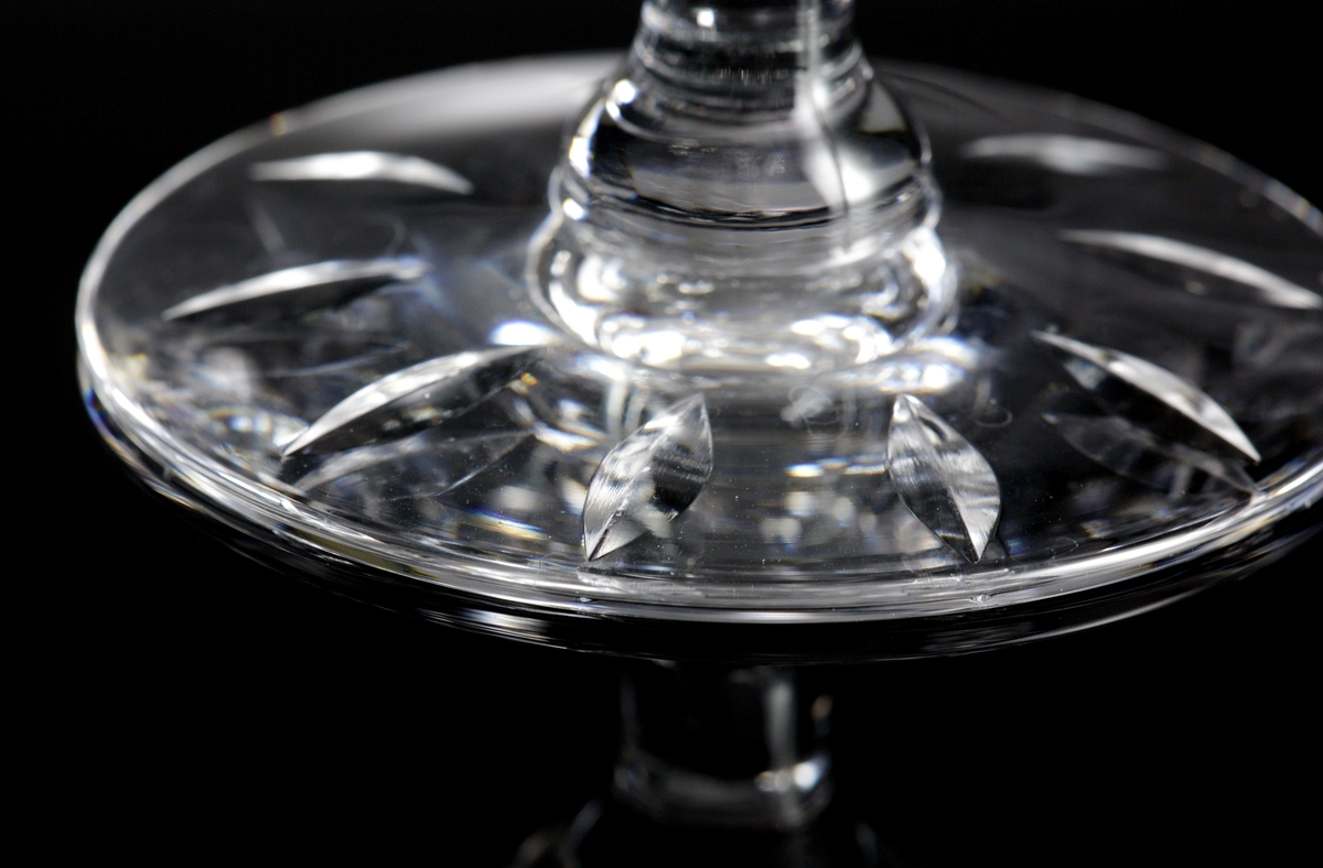 Konformad låg kupa av relativt generösa mått, ben med knapp.
På kupan stående skärslipade "spetsiga ellipser", nederst på kupen en bård av brillianter. Runt foten slipade "spetsiga ellipser".
Helkristall med högt blyinnehåll som ger tyngd åt glaset.
Fotografierna: David Lönnquist under sliparbetet. På gruppbilden står Lönnquist längst till höger.