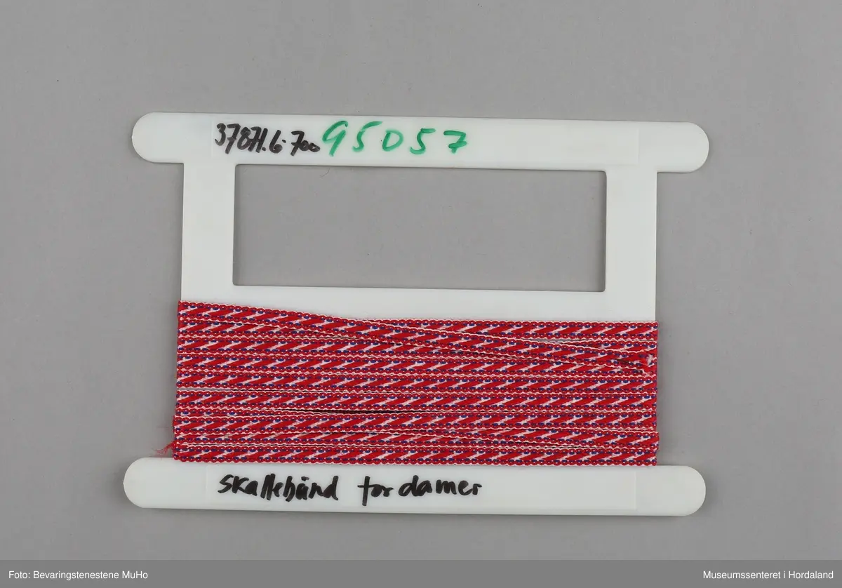 Rull med vevd band, produsert ved bandfabrikken Trengereid Fabrikker i Bergen. Banda er skalleband til samedrakt, desse til dame.