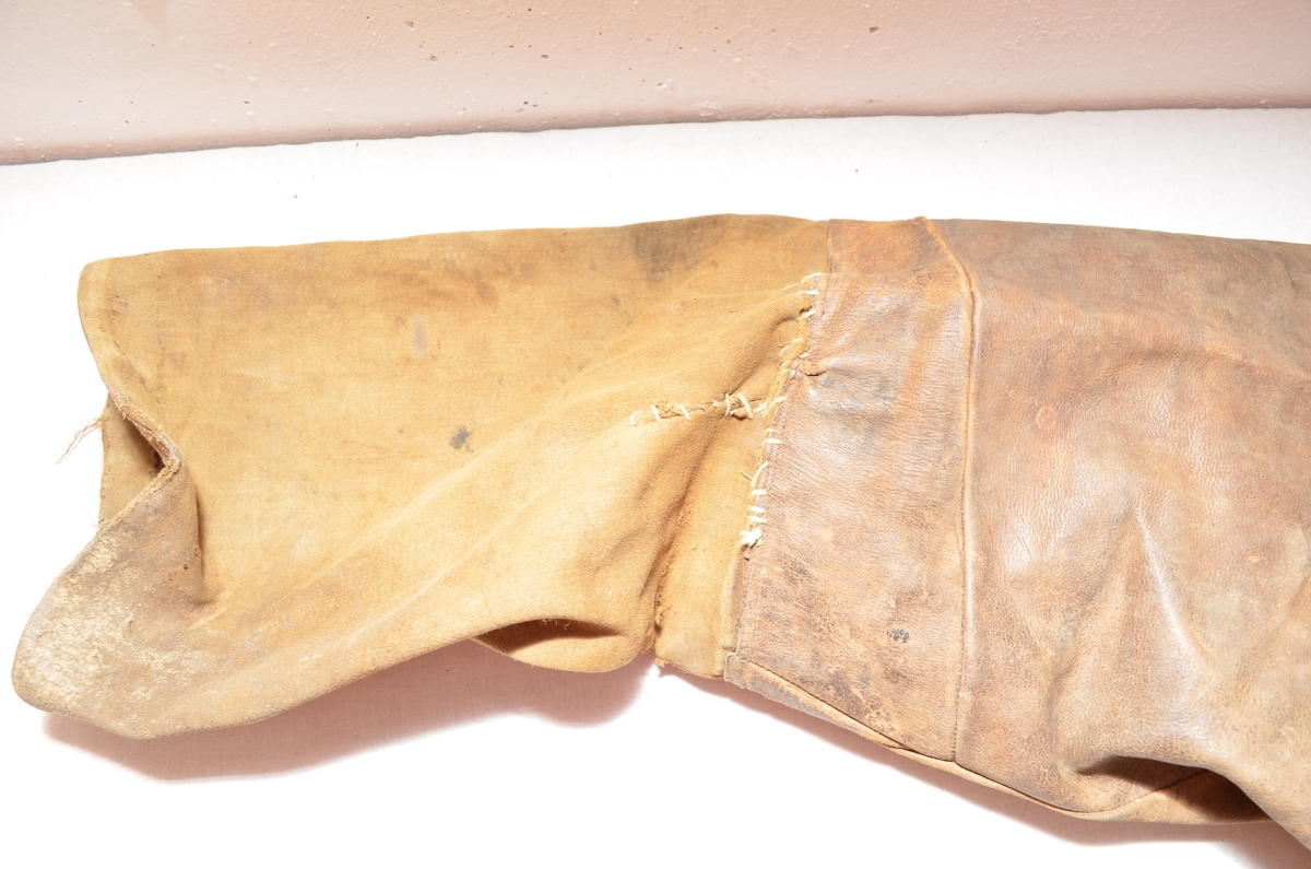 Brun skinnbrok (langbrok). Nedre del av buksebeina er i brunt bomulltøy. (26 cm). (Kan det ha vore kortbrok tidlegare? ) Linning og for i gylfen er i same bomullstøyet.To stikklommer framme  med blått bomullstøy på innsida. Gylf. Open saum midt bak (7 cm), hekta saman med ei skinnreim. Forskjellige knappar.