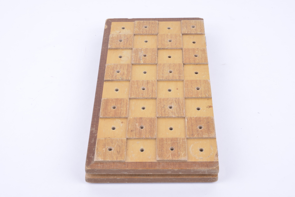 Sammenleggbar hengslet kasse i lakkert tre med brettspill på utsiden. Har tilhørende spillebrikker som ligger i en plastkrukke. 16 svarte og 16 i lakkert tre. Brikkene har pigger som kan stikkes ned i hull i brettet.