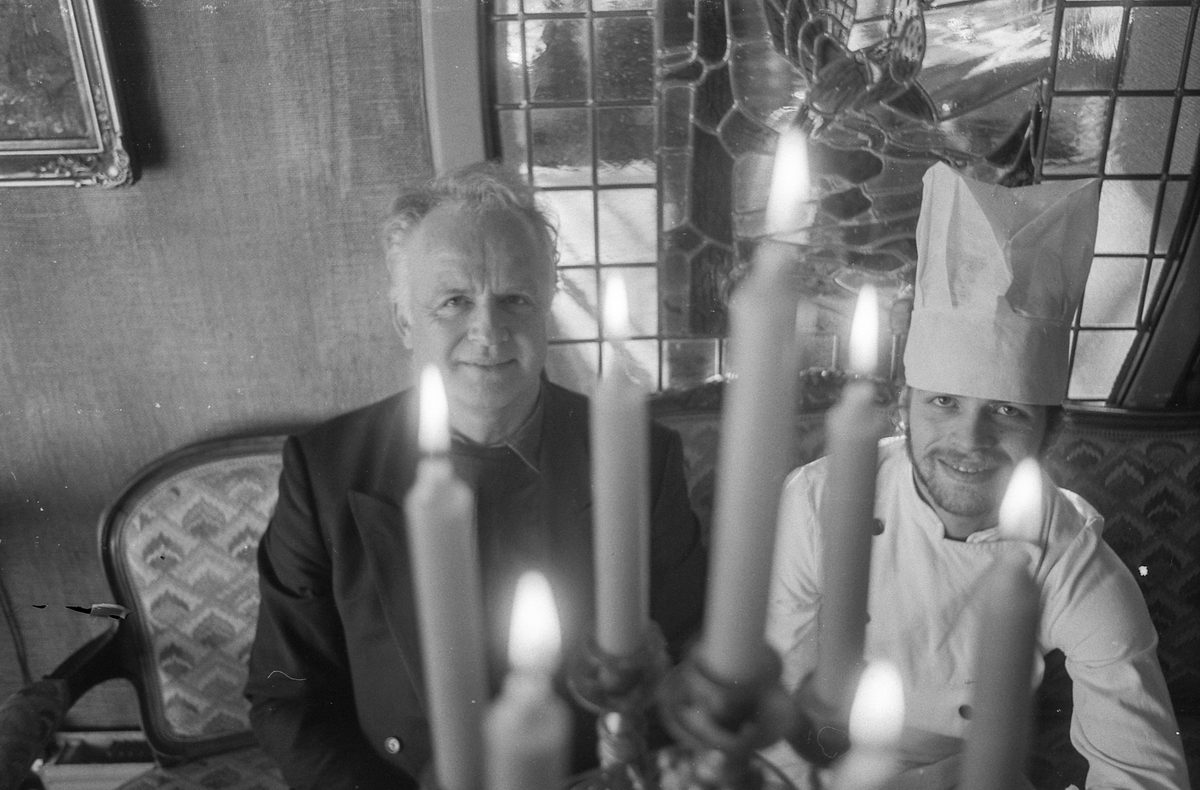 Villa Sandvigen, far John Normann Henriksen og sønn med kokkelue, sitter i restauranten ved et pent dekket bord.