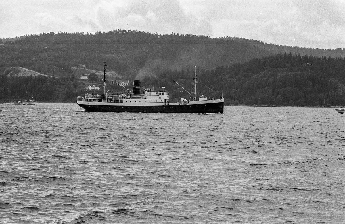 Drøbaksfjorden, sundet ved Oscarsborg. Tre menn på brygga ser på båtene med kikkert. Sandtaket og småhus på Hurum.
Fotograf: ØB Rønning
