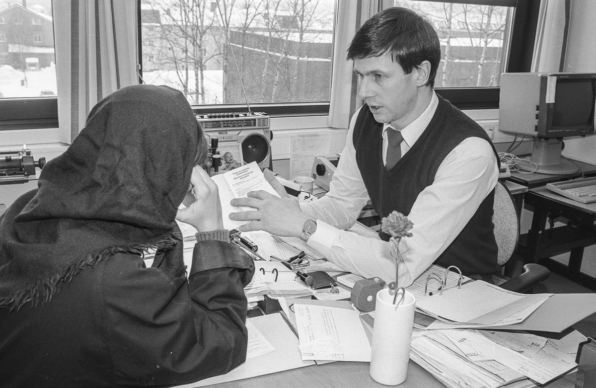 Fremmedkontoret i Ski. Politioverkonstabel Vidar Avlesen i samtale med en innvandrerkvinne i skaut. Arrangert bilde.