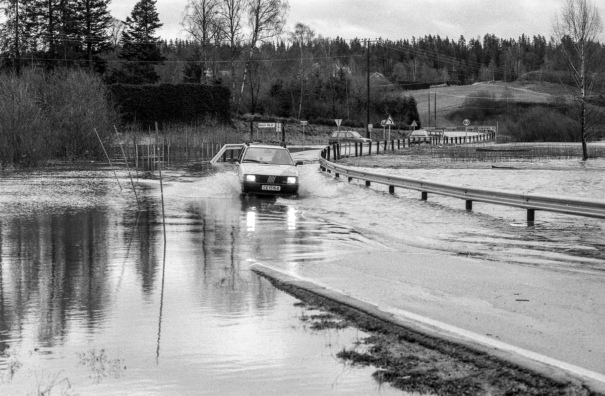 Flom i Enebakk over veier og jorder, biler kjører i flomvannet.