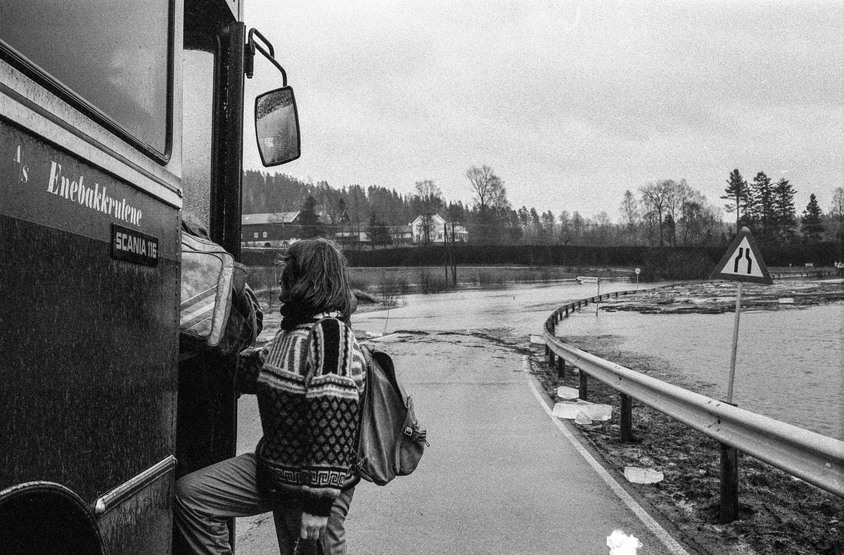Flomskader på veiene, Riksvei 120, Ytre Enebakk. Vannet flommer over veier og jorder, biler kjører så vannspruten står.