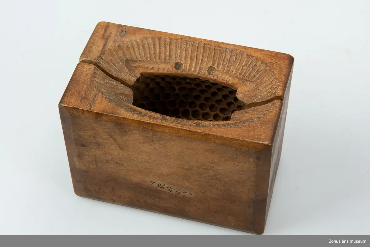 Tvådelad smörform som formar smöret till ett liggande lamm.

Ur handskrivna katalogen 1957-1958:
Smörformare
I 2 delar, a-b, mått (hopsatt)13,5 x 10,3 x 7,8 cm, av trä, omålat; form till höna el. dyl. Hel.
