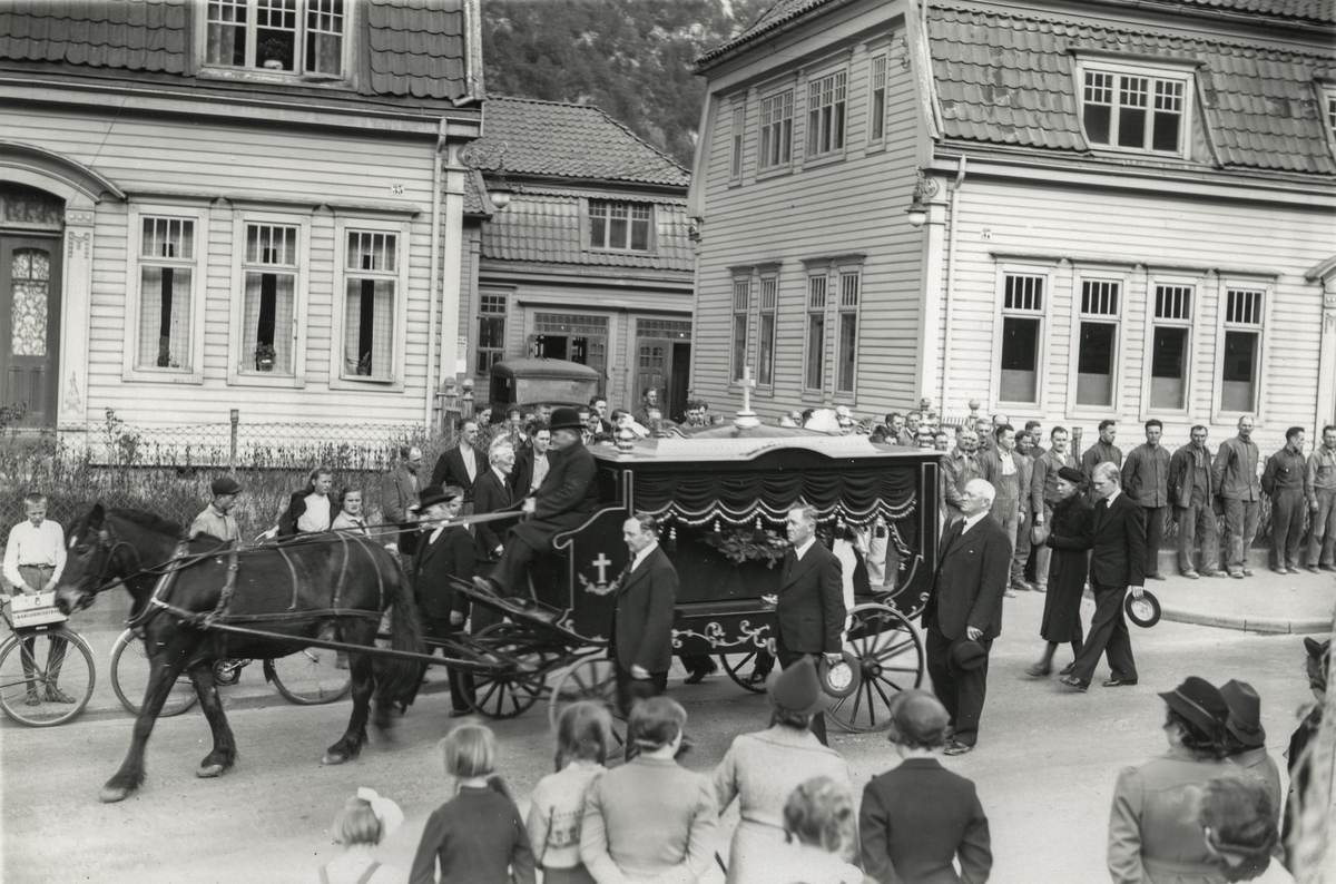 Likfølgje med hest og likvogn for ingeniør Harald Georg Rosengren passerer Porten og kontorbygg på Odda Smelteverk.