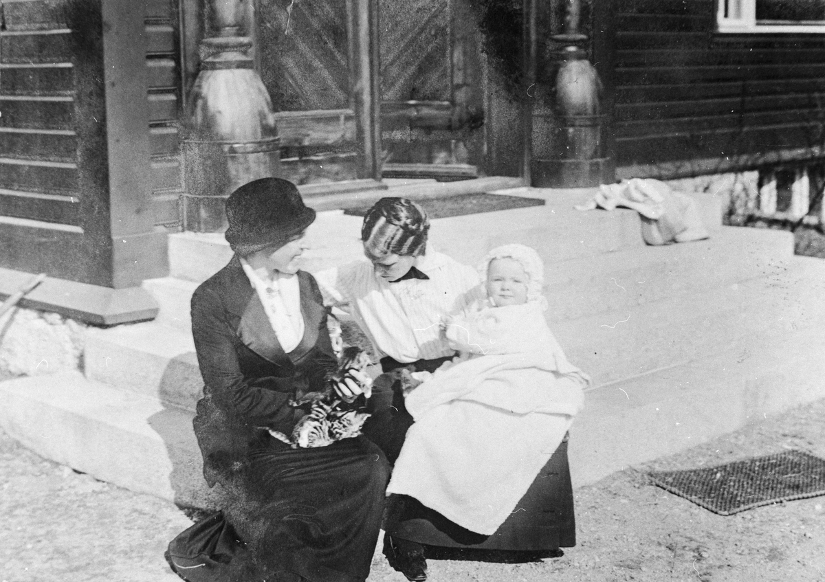 To kvinner med  ein baby på trappa til Brucevillaen.