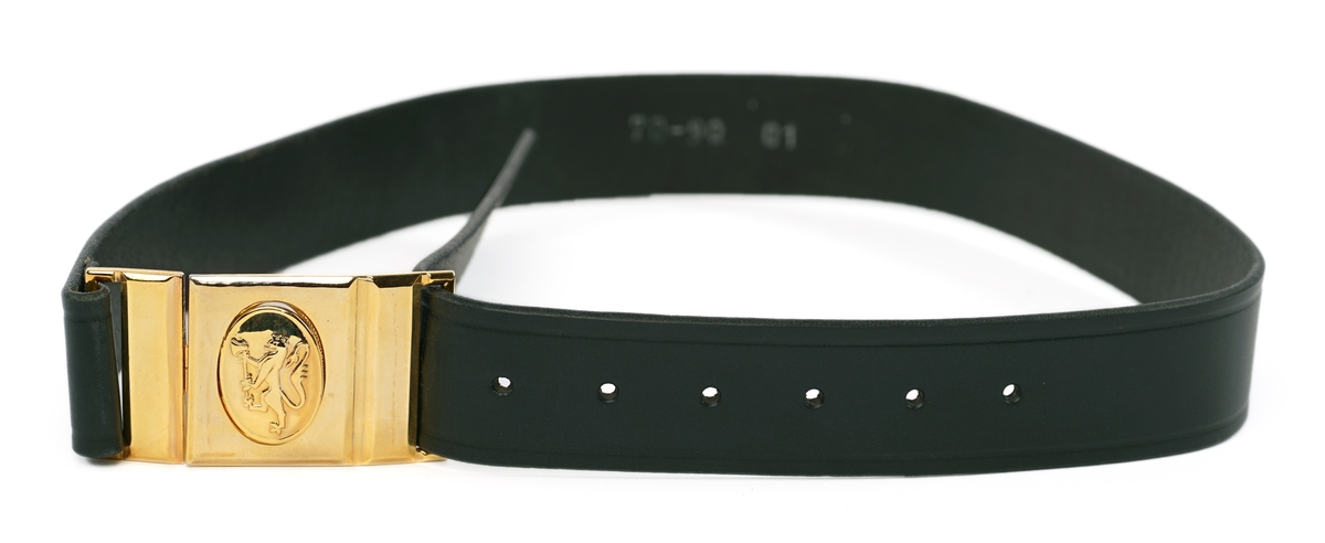 Mørkblå dame jakke enkelspent med fire riksløveknapper. Epauletter med merkurstav, krone, og to kvist eikblader (fire blader totalt) mellom to gullbånd. Tekstil marke på begge armer, krone over riksløve med hvit øks i rød skjold omgitt av eikeblader over TOLL/CUSTOMS. Hempe i nakke. Kypert stoff, blanding av polyester og ull. Jakke er foda med antatt syntetisk stoff, sort.
Hvit hatt med sort visir. Metall distinkjons skilt av krone over riksløve med søkvferget øks i rød skjold omgitt av eikeblader. Gullfletting over visir, og eikeblader på visir.
Lys blå dame skjorte med matchende distinktsjoner og tekstil merker på armene.