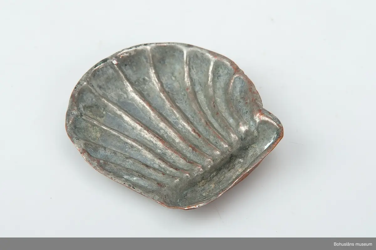 Ur handskrivna katalogen 1957-1958:
Liten kopparform
Mått c:a 8,5 x 7,9 cm. Tio "strålar" utgående från ett gemensamt horisontalt fäste. Föremålet relativt helt.

Lappkatalog: 59