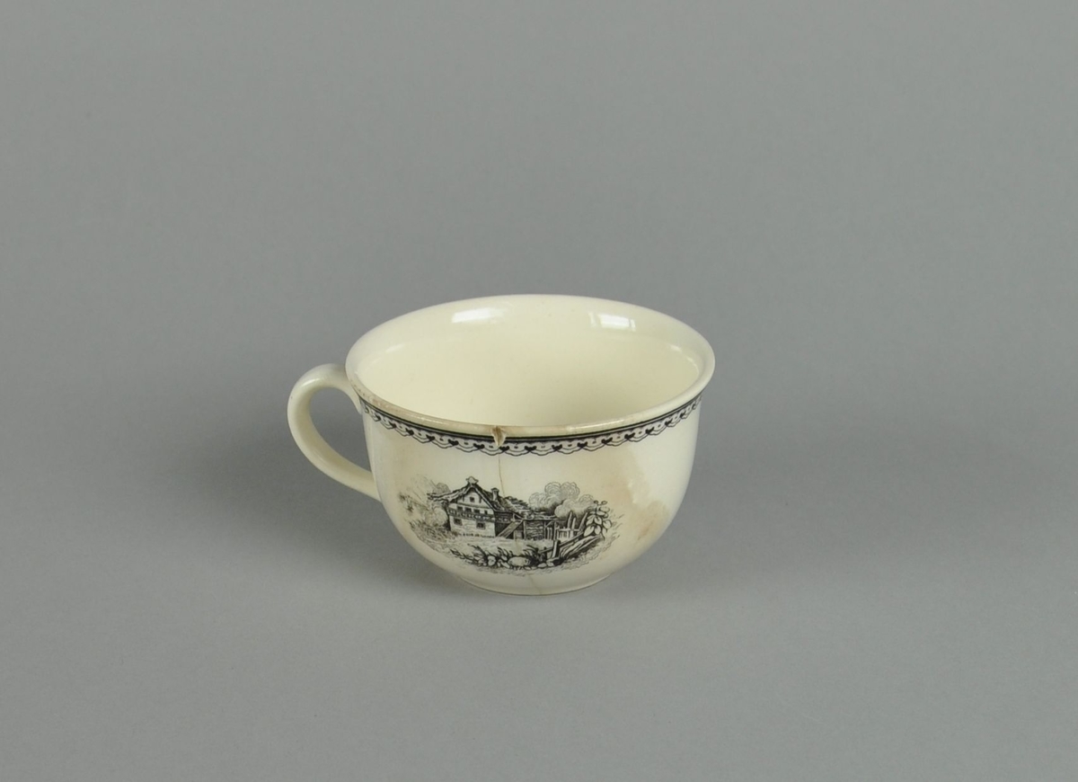 Kopp av glassert keramikk, med hank. Svart dekortrykk av klosterruiner og gård, samt en borde langs randen. Koppen har en synlig sprekk.