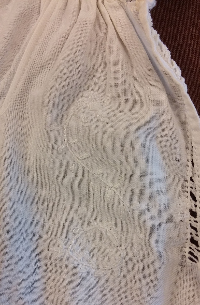 Rødt underskjørt med kappe og lomme, brodert linskjorte, brodert ull-skjørt, brodert ull-vest, brodert lue, brodert veske og blått brodérgarn i ull.