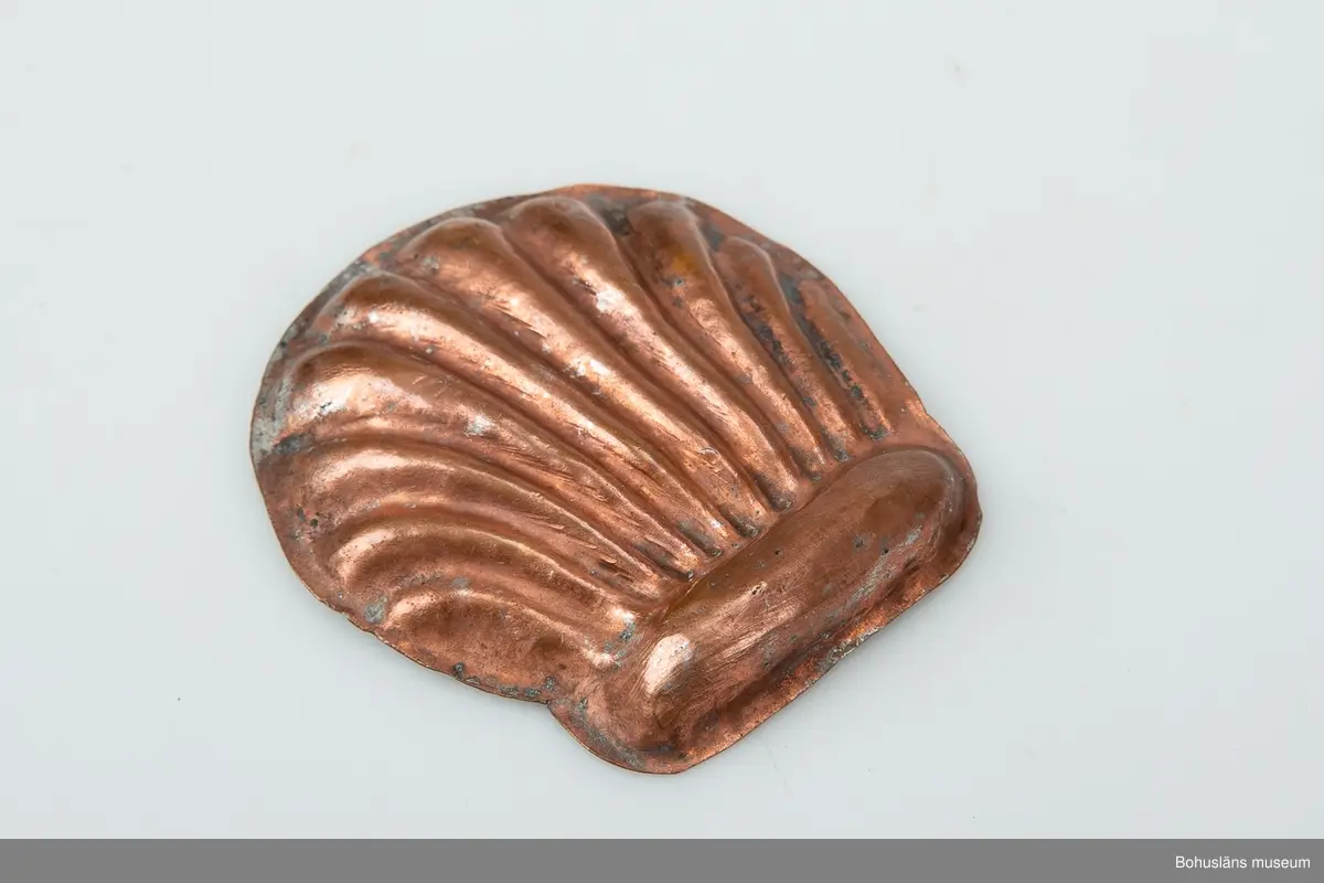 Ur handskrivna katalogen 1957-1958:
Liten kopparform
Mått c:a 8,5 x 7,9 cm. Tio "strålar" utgående från ett gemensamt horisontalt fäste. Föremålet relativt helt.

Lappkatalog: 59