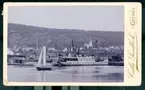 Kabinettsfotografi: Gränna hamn från sjösidan. Okänt ångfartyg vid kaj, en segelbåt drar förbi.