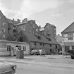 Miljö från kvarteret Blandaren i Linköping 1965. Bilden visar platsen bakom Sankt Larsgatan 15. Adressen är Kungsgatan 29 och rymmer förutom auktionshus och gummiverkstad även ett uttjänt stall. Dokumentation av Östergötlands museum inför sanering.