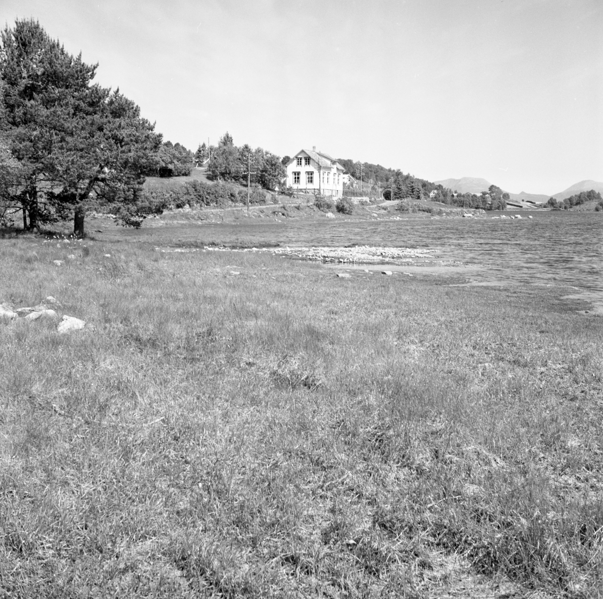 Prospektfotografi av Eikremsvegen ved Mausavatnet, Sula. En eldre skole står ved vannet.