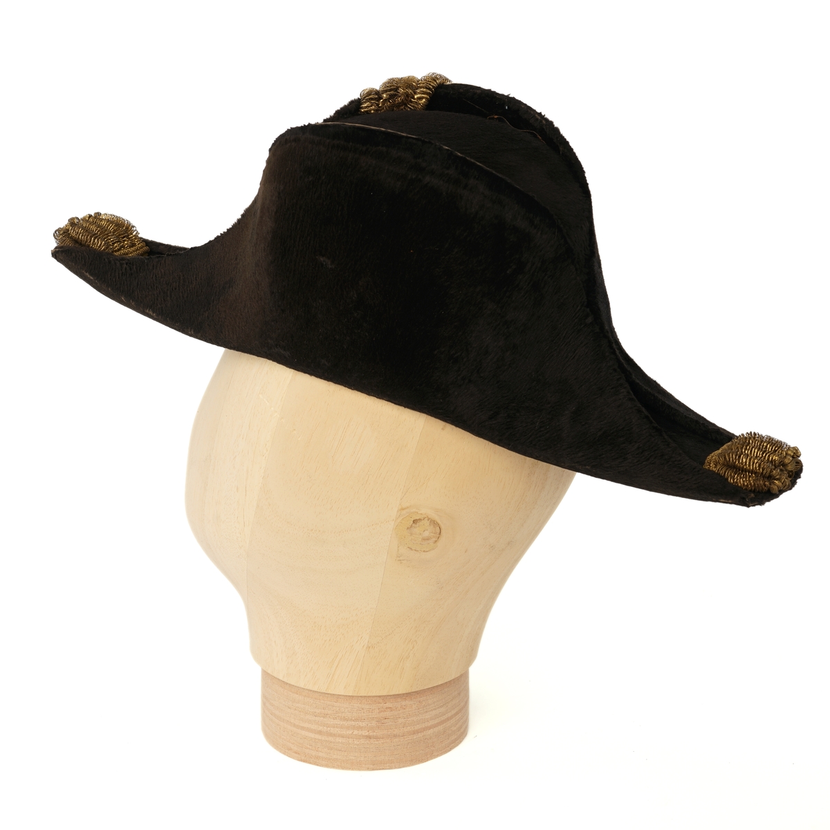 Snutehatt av sort, velurlignende stoff. Rød-hvit-blå kokarde, gulltresse med riksløveknapp. Gullpynt i hver snute. Brunn skinn til svetterem, lys lilla silkefôr. 
Metall hatteske til snutehatt.