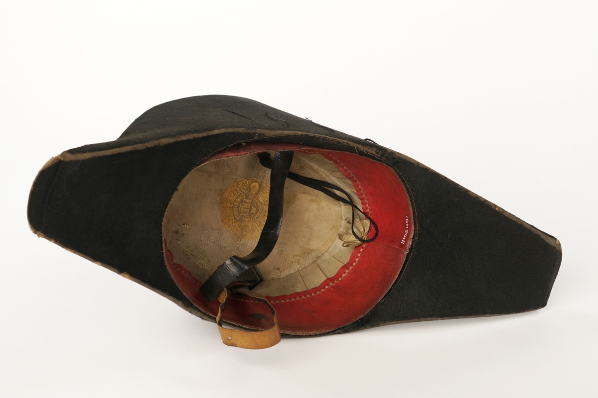 Snutehatt av sort, velurlignende stoff. Rød-hvit-blå kokarde, krysset med sortbånd festet med riksløveknapp. Fire tynne sorte snorer på hver side. Rødt skinn til svetterem, hvit silkefôr. Hvit knapp i toppen av innsiden pull. Sort lær hakerem.
Metall hatteske til snutehatt.