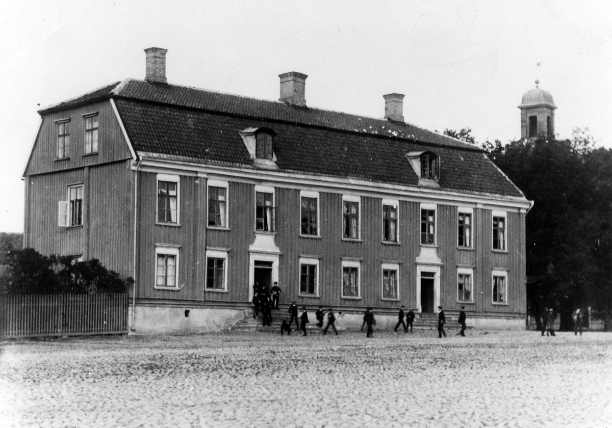 Rådhuset där läroverket var inrymt vid sekelskiftet 1800-1900. En stor grupp barn syns utanför byggnaden.