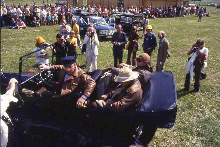 Ballongfestival 1973 i Gränna. En veteranbil, cabriolet, anländer med tre män i läderrockar, i baksätet med ljus hatt Hans Alfredsson.