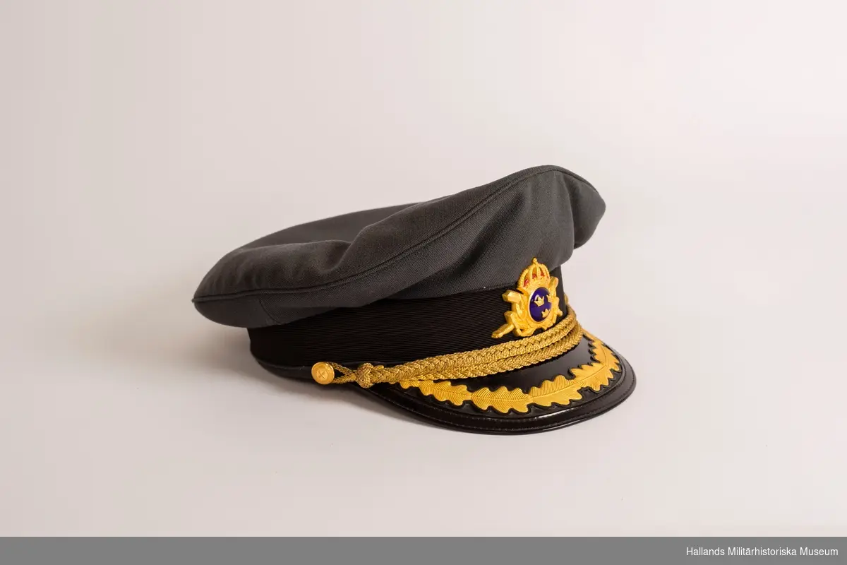 En skärmmössa för officer i stålgrått tyg. Mössan har svartlackerad skärm och mörkt stålgrått mössband kring stommen. Mössrem för generalpersoner och regementsbefäl, tillverkad i tjock flätad guldtråd. Mössremen är fäst i två små knappar ( guld m/1767) på vardera sidan av mössan. Knapparna bär Generalstabens emblem (två korslagda kanoner). Mössmärke till skärmmössa m/60, för officer på framsidan av mössan samt skärmbroderi för generalsperson vilken betecknas med en eklövskrans. Svart botten inuti, tillverkarens etikett på botten samt ägarens namnlapp.