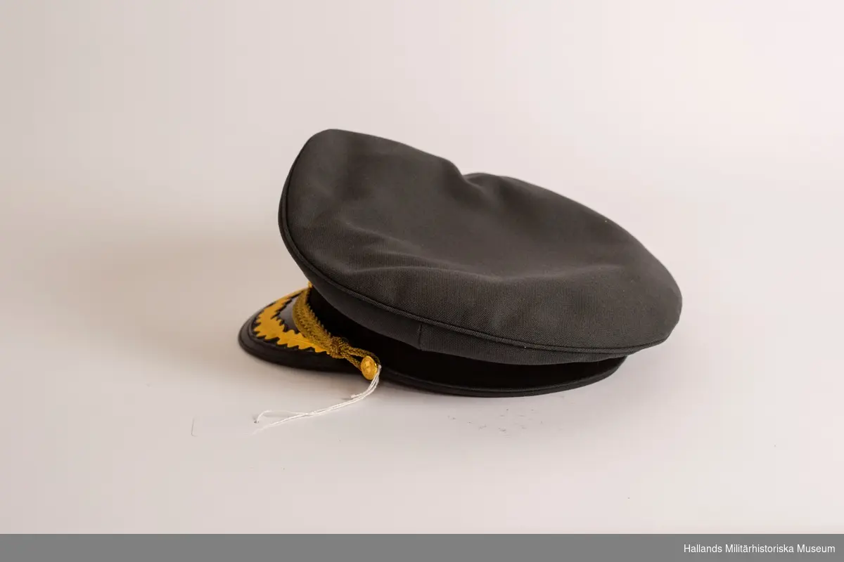 En skärmmössa för officer i stålgrått tyg. Mössan har svartlackerad skärm och mörkt stålgrått mössband kring stommen. Mössrem för generalpersoner och regementsbefäl, tillverkad i tjock flätad guldtråd. Mössremen är fäst i två små knappar ( guld m/1767) på vardera sidan av mössan. Knapparna bär Generalstabens emblem (två korslagda kanoner). Mössmärke till skärmmössa m/60, för officer på framsidan av mössan samt skärmbroderi för generalsperson vilken betecknas med en eklövskrans. Svart botten inuti, tillverkarens etikett på botten samt ägarens namnlapp.