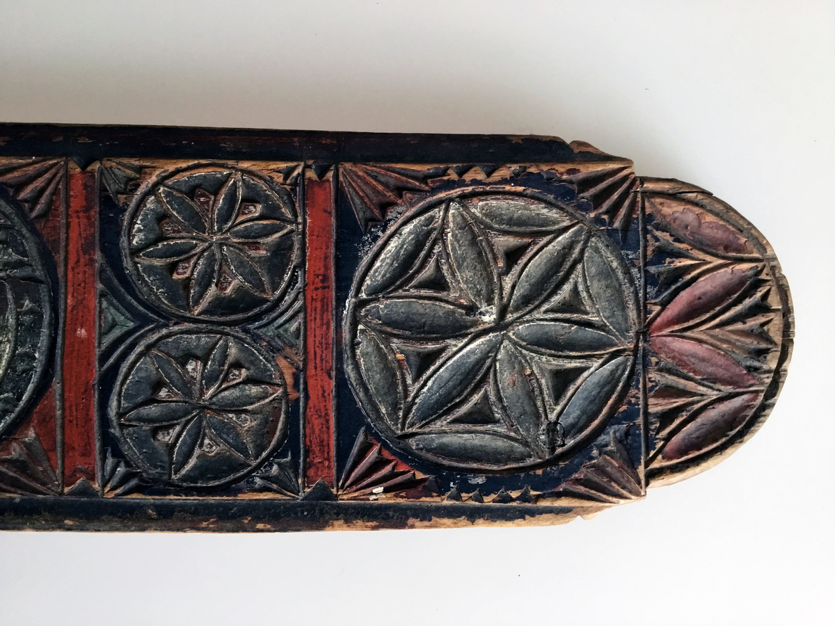 Mangletreet er malt rødt, sort og kvitt. Karveskurd. Hestehåndtak. Afrundet foran. Dekorert med store og små seksbladsroser.