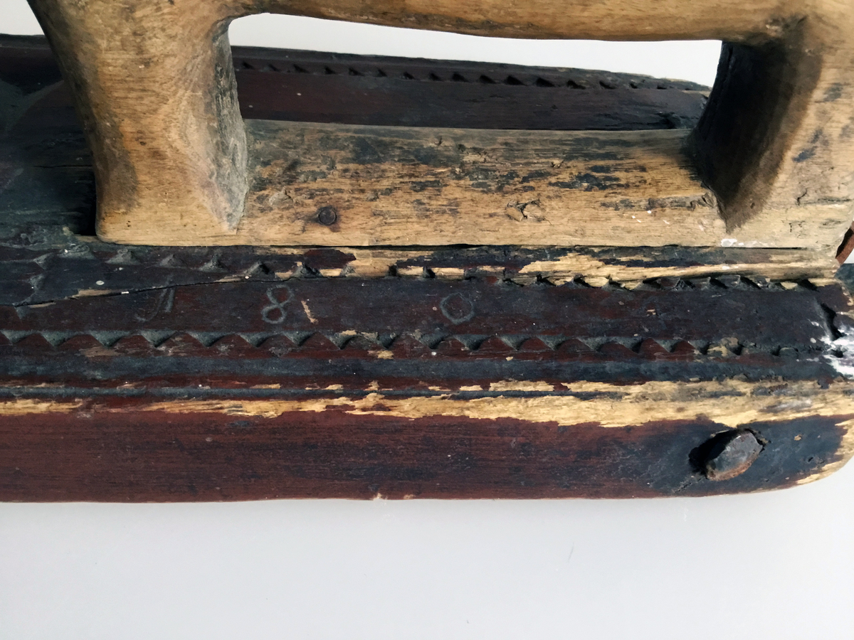 Mangletreet er malt rødt med to gule rosetter. Dekortert med store og små rosetter med seksbladsroser, og sikksakkbord ved håndtaket. Hestehåndtak. Datert 1804. Håndtaket er nyere og trefarget. Lærhempe i enden.