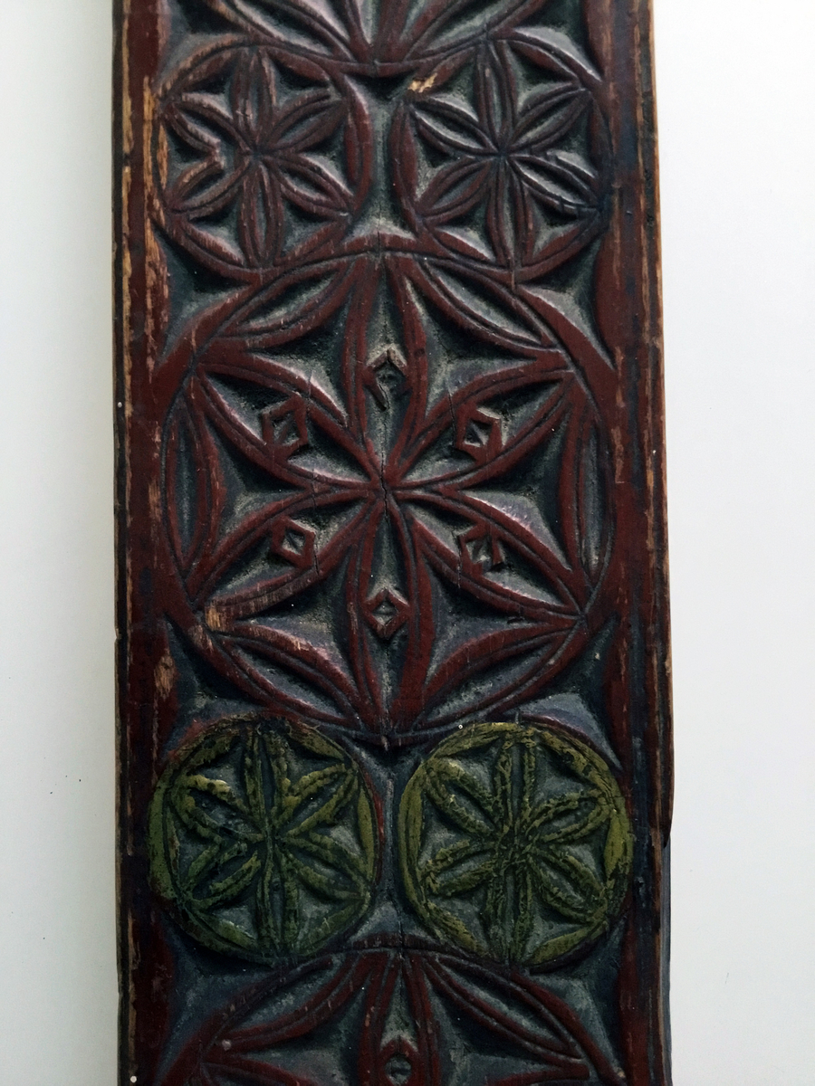 Mangletreet er malt rødt med to gule rosetter. Dekortert med store og små rosetter med seksbladsroser, og sikksakkbord ved håndtaket. Hestehåndtak. Datert 1804. Håndtaket er nyere og trefarget. Lærhempe i enden.