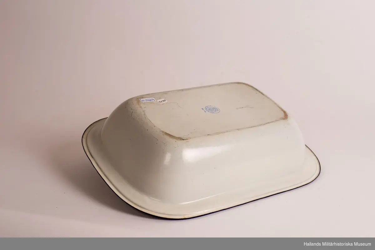 Ett djupt fat. rektangulärt, vit och med blå kanter. Emaljerad metall. Fabriksmärkt på undersidan. 30 cm.
