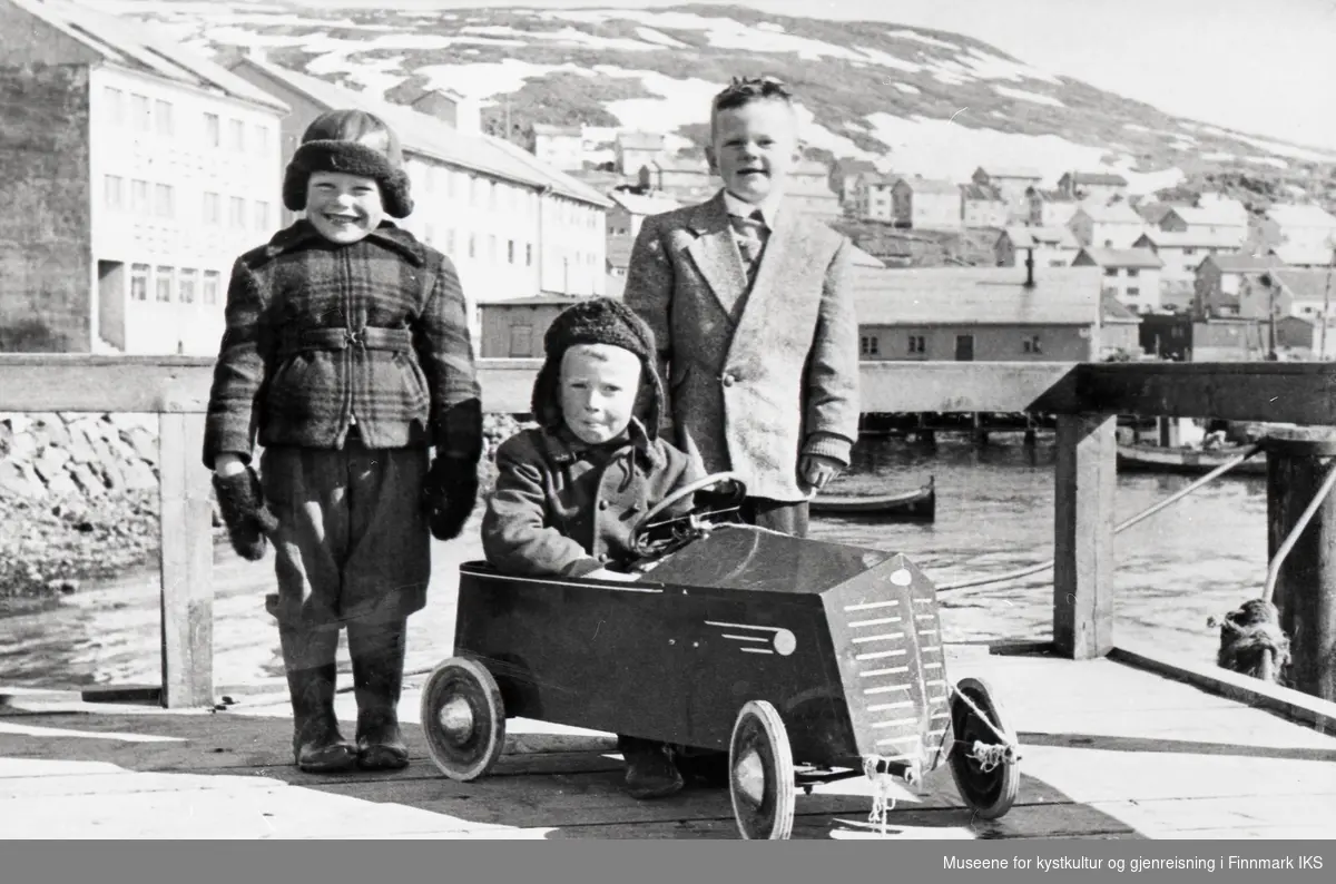 Honningsvåg. F.v. Per Ingvart Aronsen, Reidar Andreas Elde sittende i bilen og Brynjar Elde på "Honnørbrygga". 1956/1957.