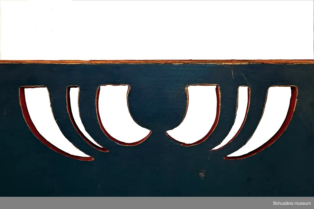 Träsoffa med ryggspjälor med genomsågade hål i form av hjärtan. Överstycke med genombruten dekor i geometrisk form. Sidostycken med genombruten dekor av jugendkaraktär. Blå- och rödmålad. 
Denna och liknande soffor och stolar tillverkades i sjukhusets snickeri av patienter och anställda förmän till sjukhusets korridorer, dagrum,   
patientsalar o.dyl.