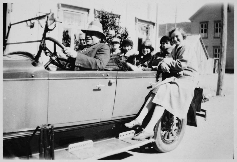 Gruppebilde av flere personer som sitter i en Chrysler Roadster.