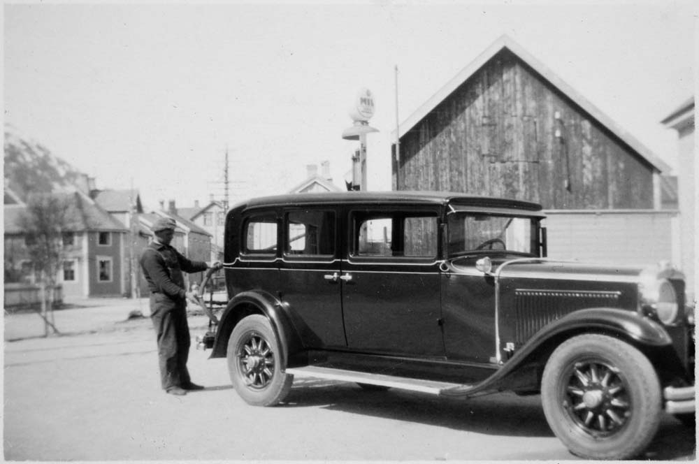 Person fyller bensin i Mosjøen, kan være Chrysler Roadster (1928-modell?).